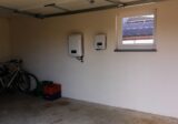 Magazyn energii i falownik na ścianie garażu domu z instalacją fotowoltaiczną