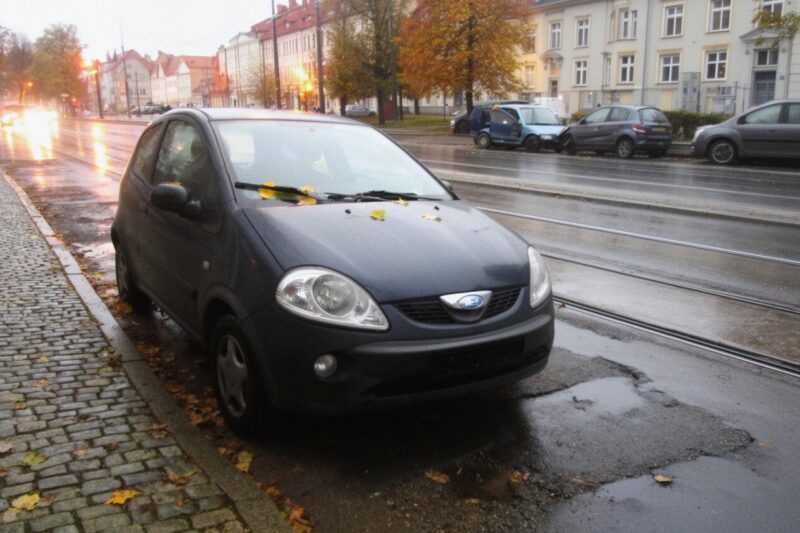 Zaparkowane auto przy ulicy z torowiskiem tramwajowym w deszczowy jesienny wieczór