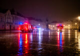 Światła służb odbite w mokrym rynku