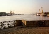 Nabrzeże nad szeroką rzeką z dźwigami portowymi po drugiej stronie wieczorem
